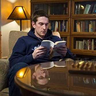 A student reads a book in a classic library study