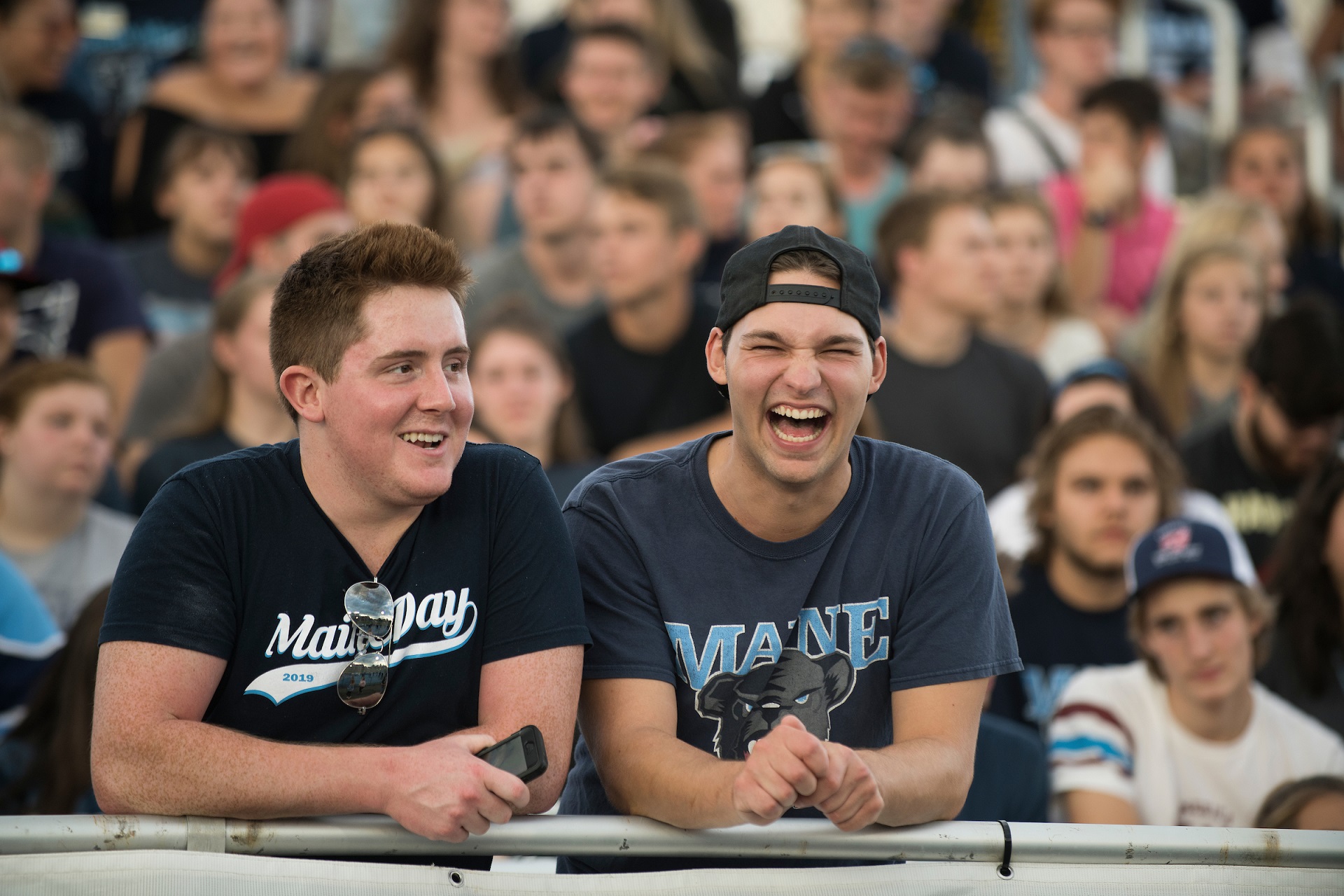 Two students in a crowd wearing UMaine shirts