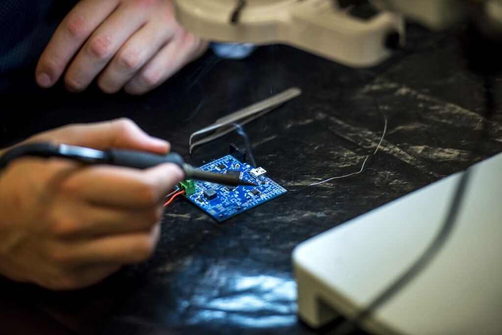 A close up of a soldering iron applying solder to a circuit board