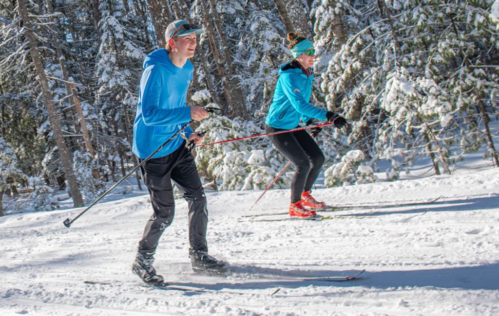 A photo of two people cross country skiing on UMaine's trails