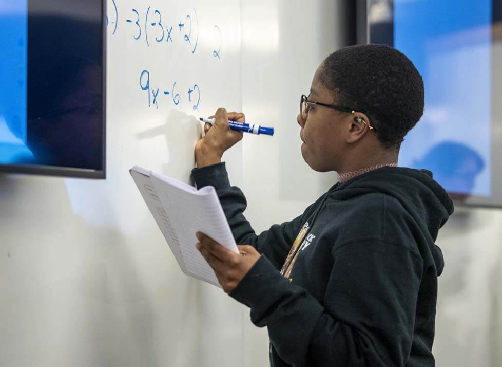A photo of a student working on a math problem on a white board