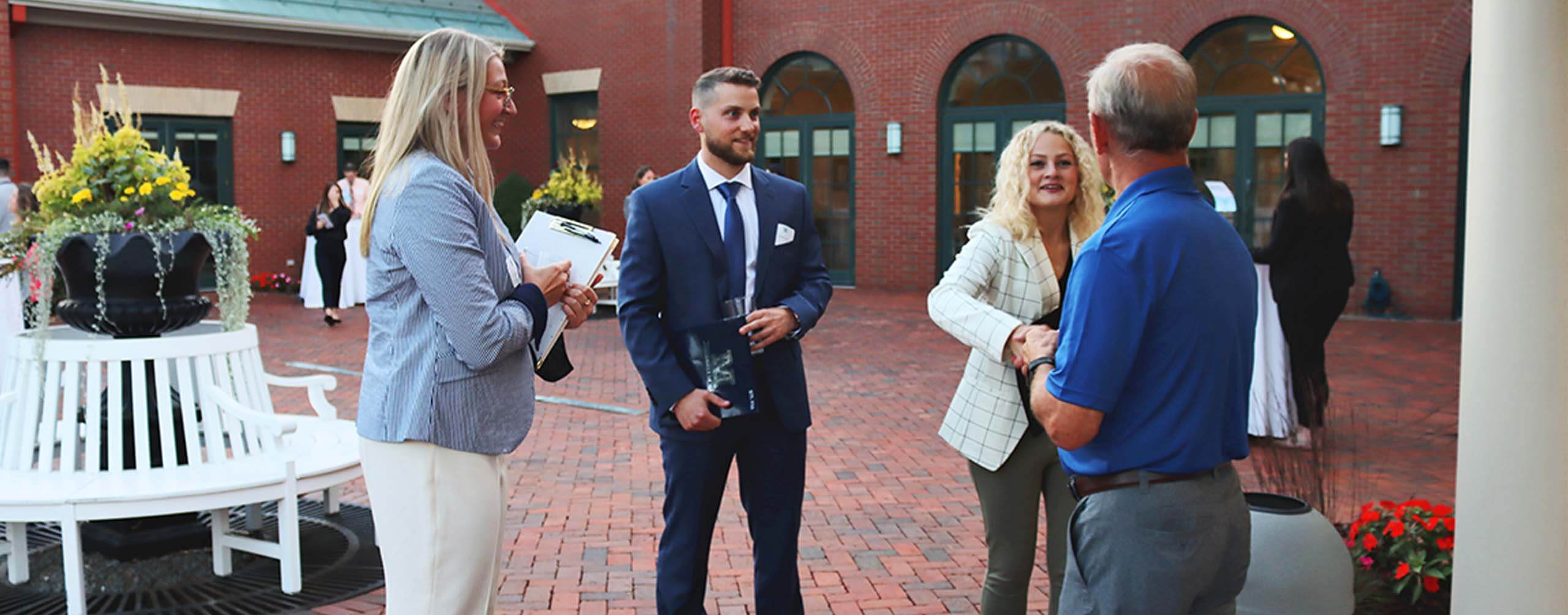 A photo of people standing in a brick courtyard wearing business apparel
