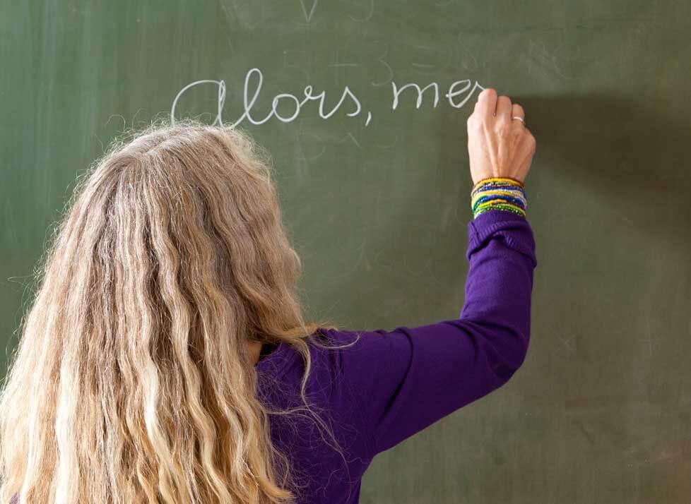 A photo of a person writing on a chalk board
