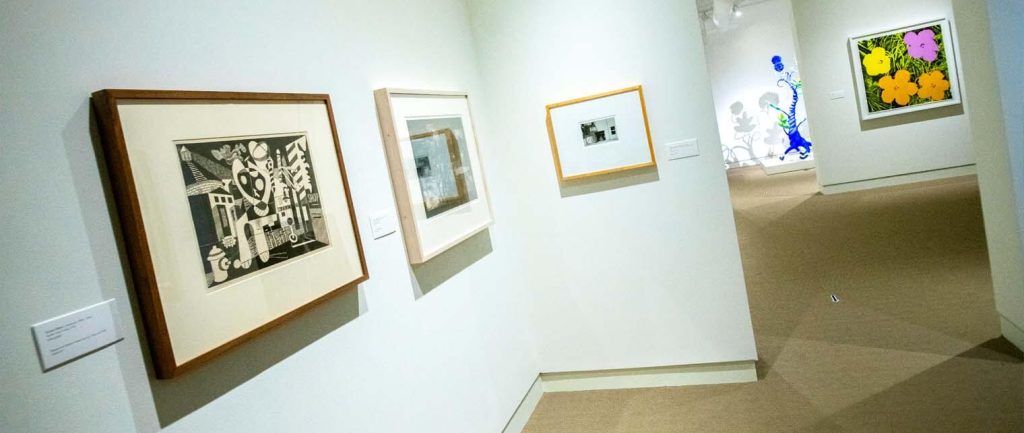 A photo of artwork on a white wall in a gallery