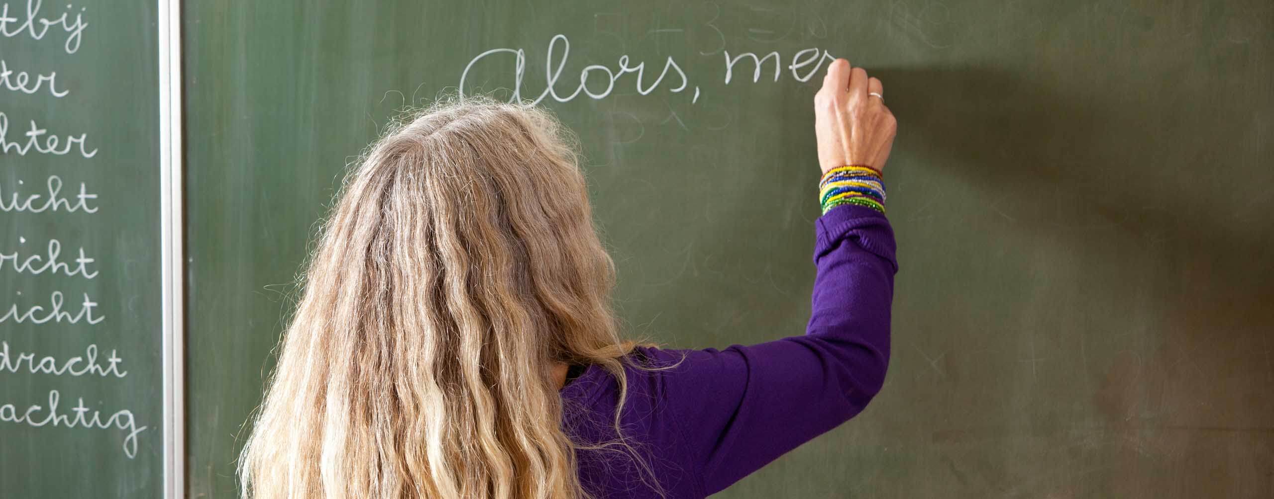 A photo of a person writing on a chalk board