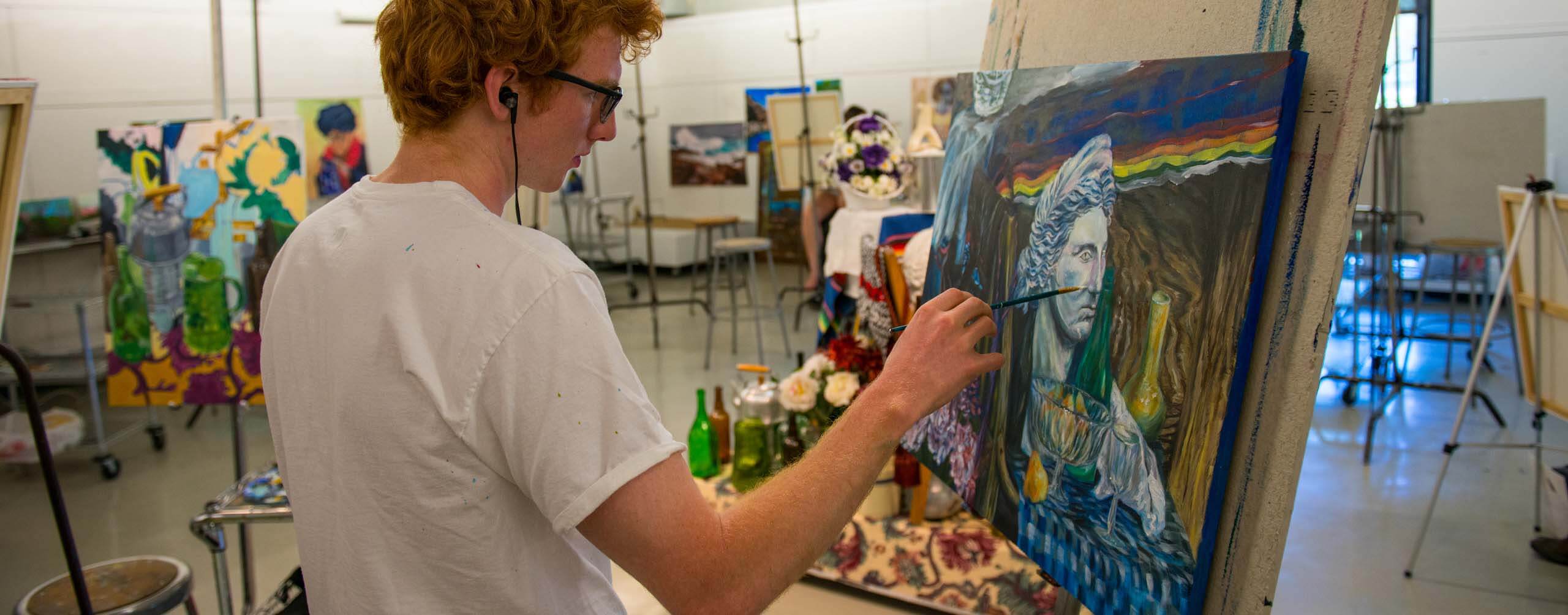 A photo of a student artist painting on a canvas