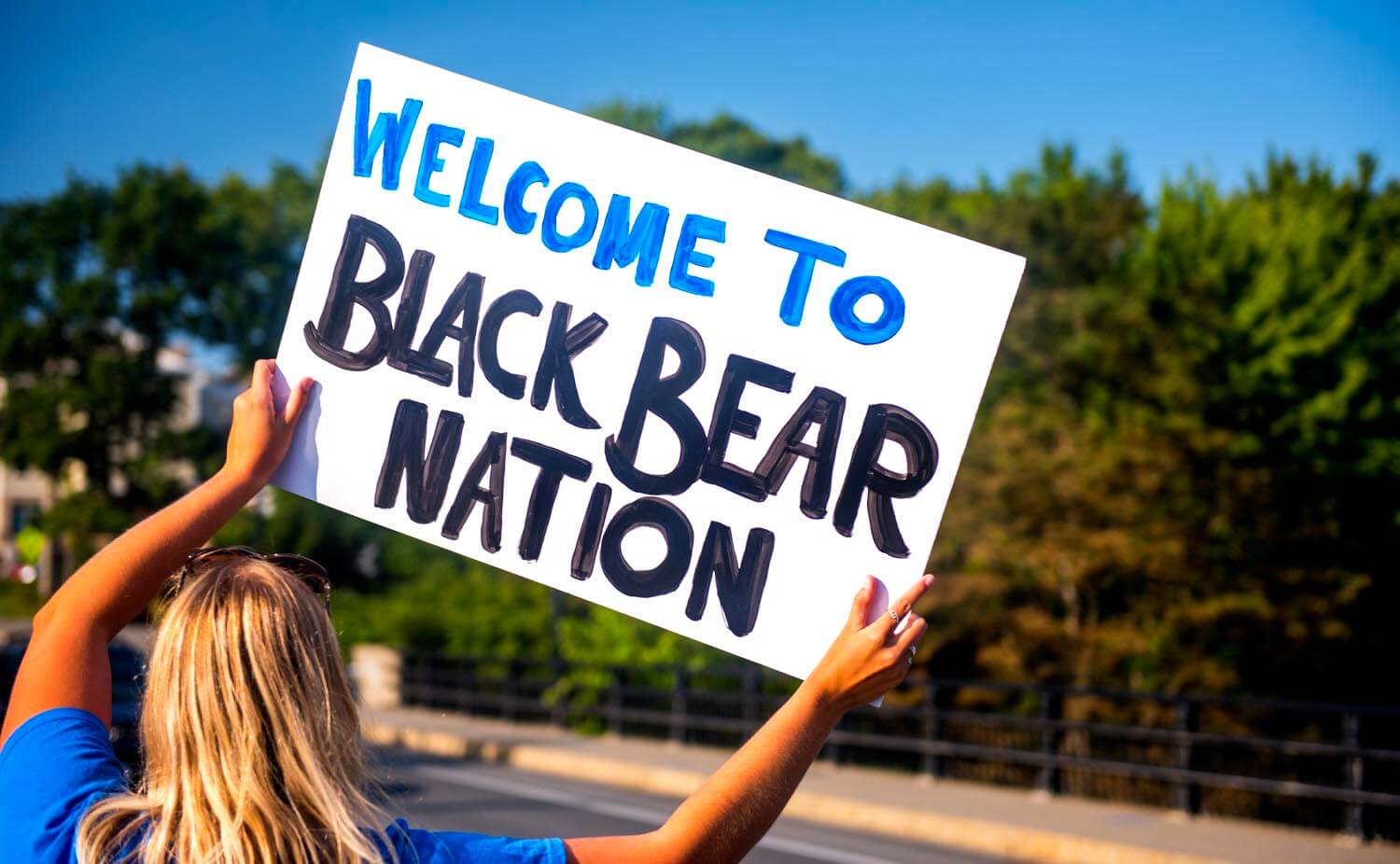 A photo of a person holding up a sign that says "Welcome to Black Bear Nation"